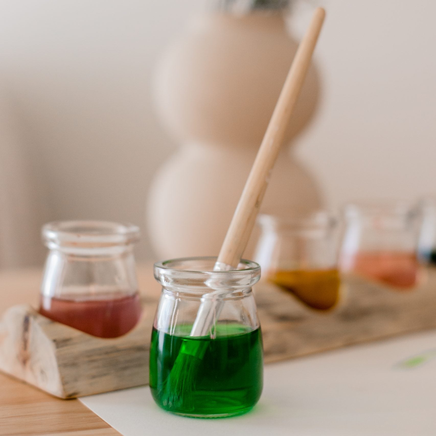 Glass jar with green liquid on a wooden surface with a blurred background