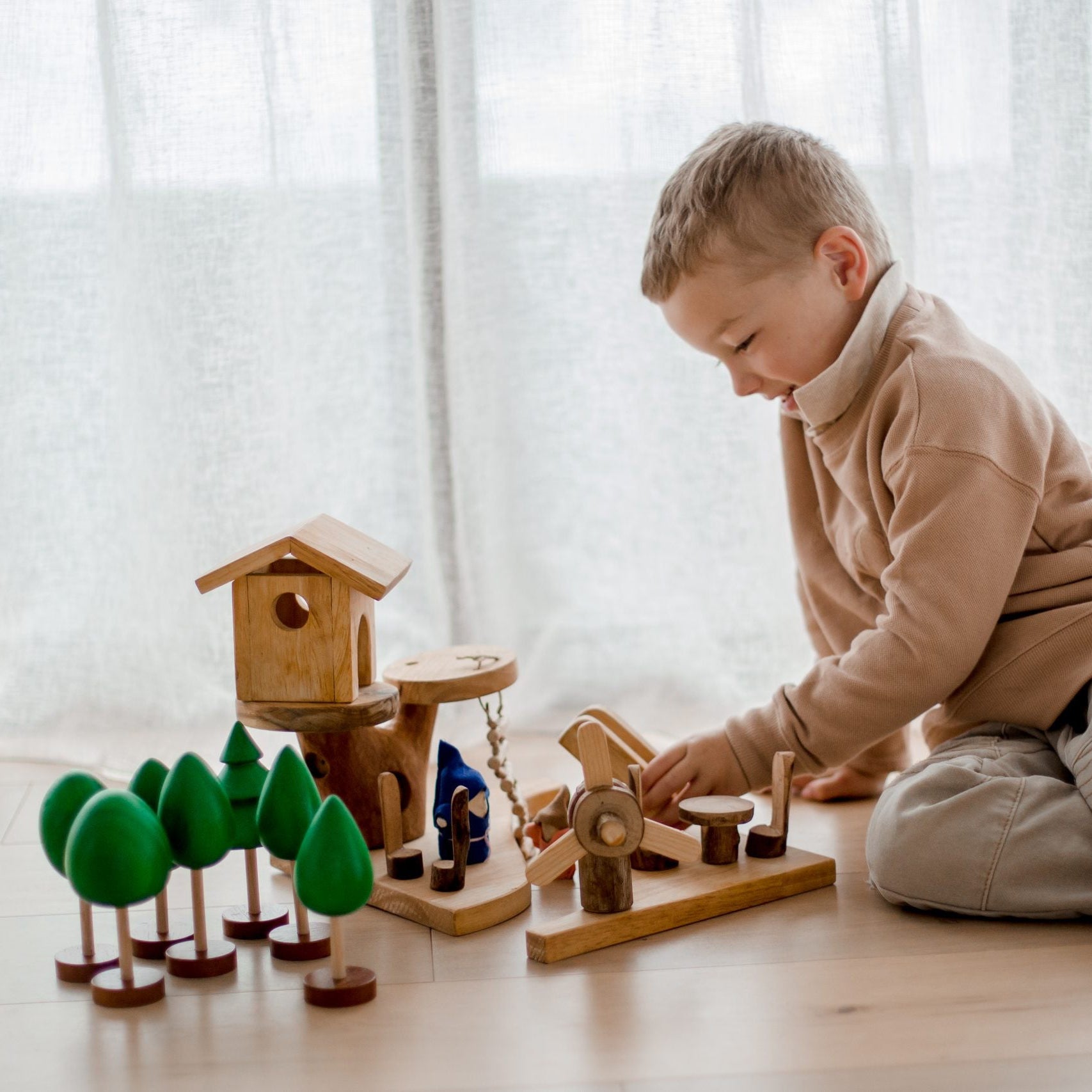 Child playing with wooden toys on a wooden floor in a bright room.