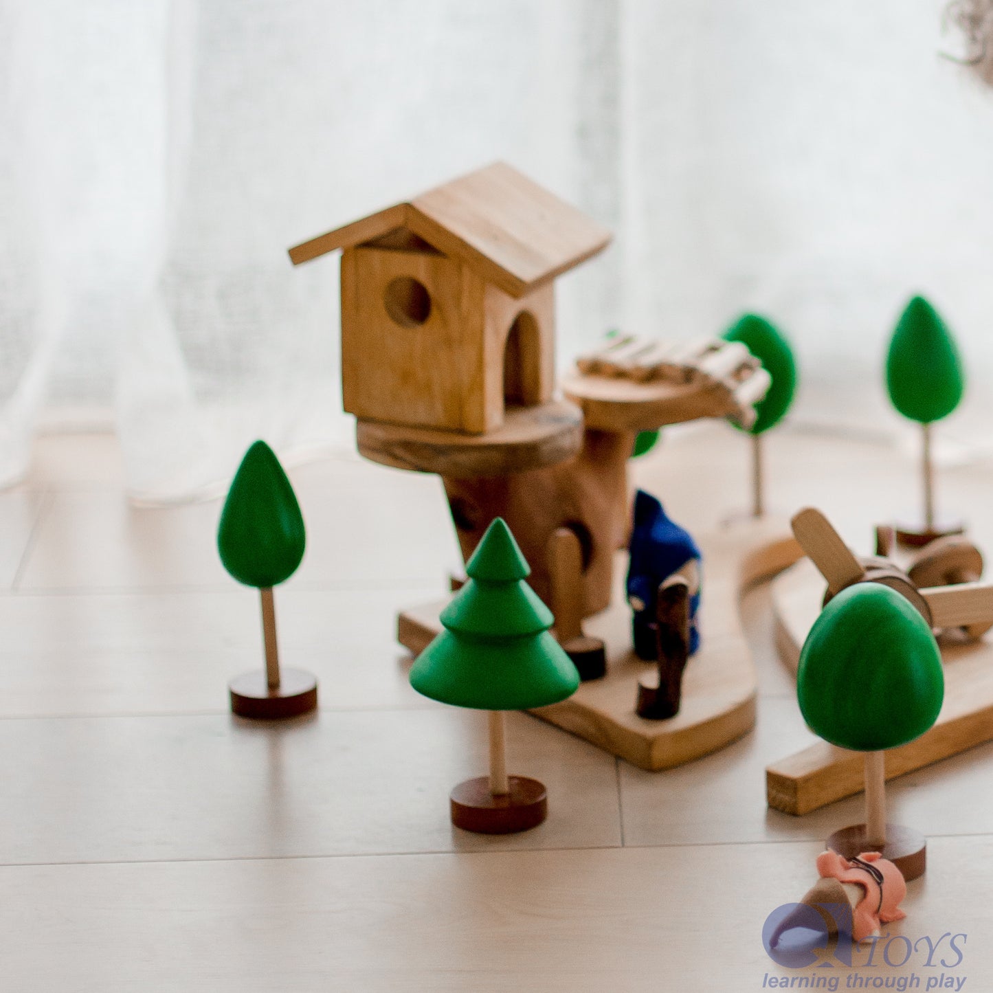 Wooden toy birdhouse with trees on a light surface