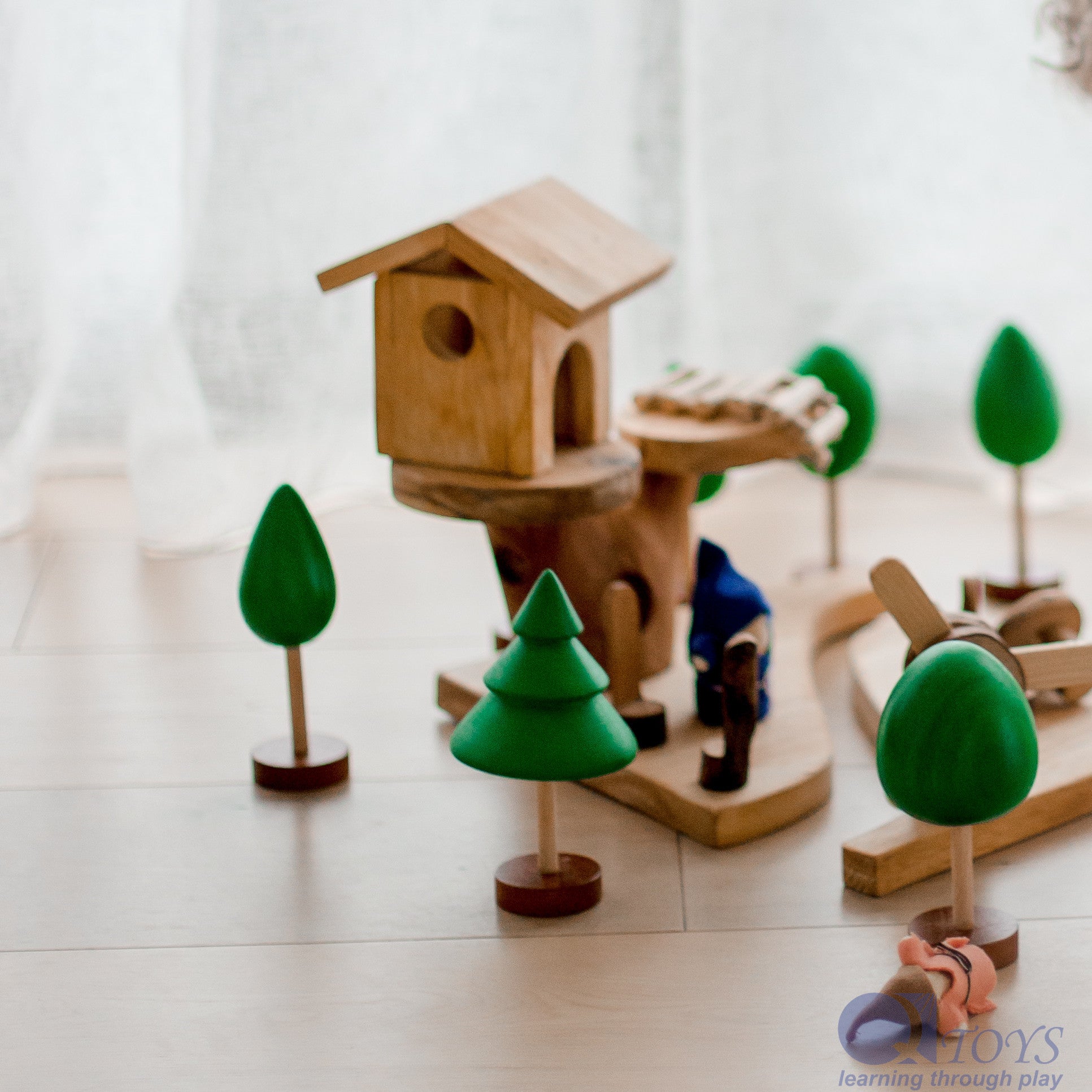 Wooden toy birdhouse with trees on a light surface
