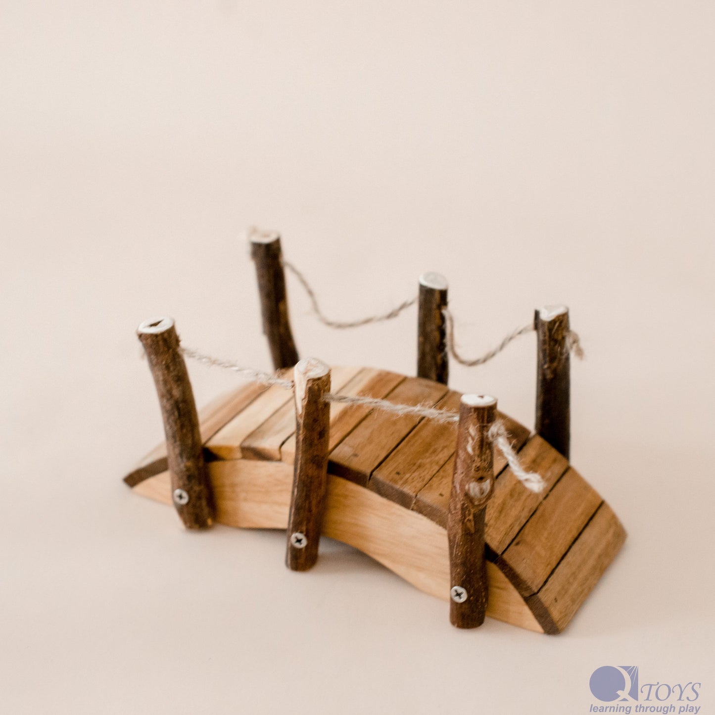 Wooden toy bridge with planks and posts on a beige background