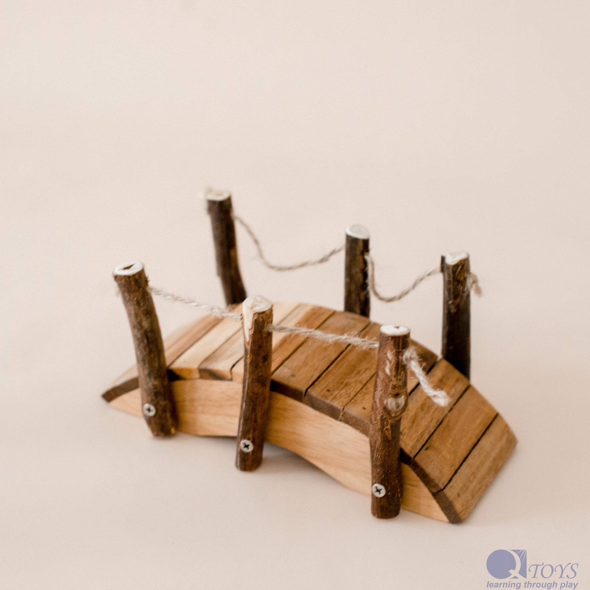 Wooden toy bridge with planks and posts on a beige background