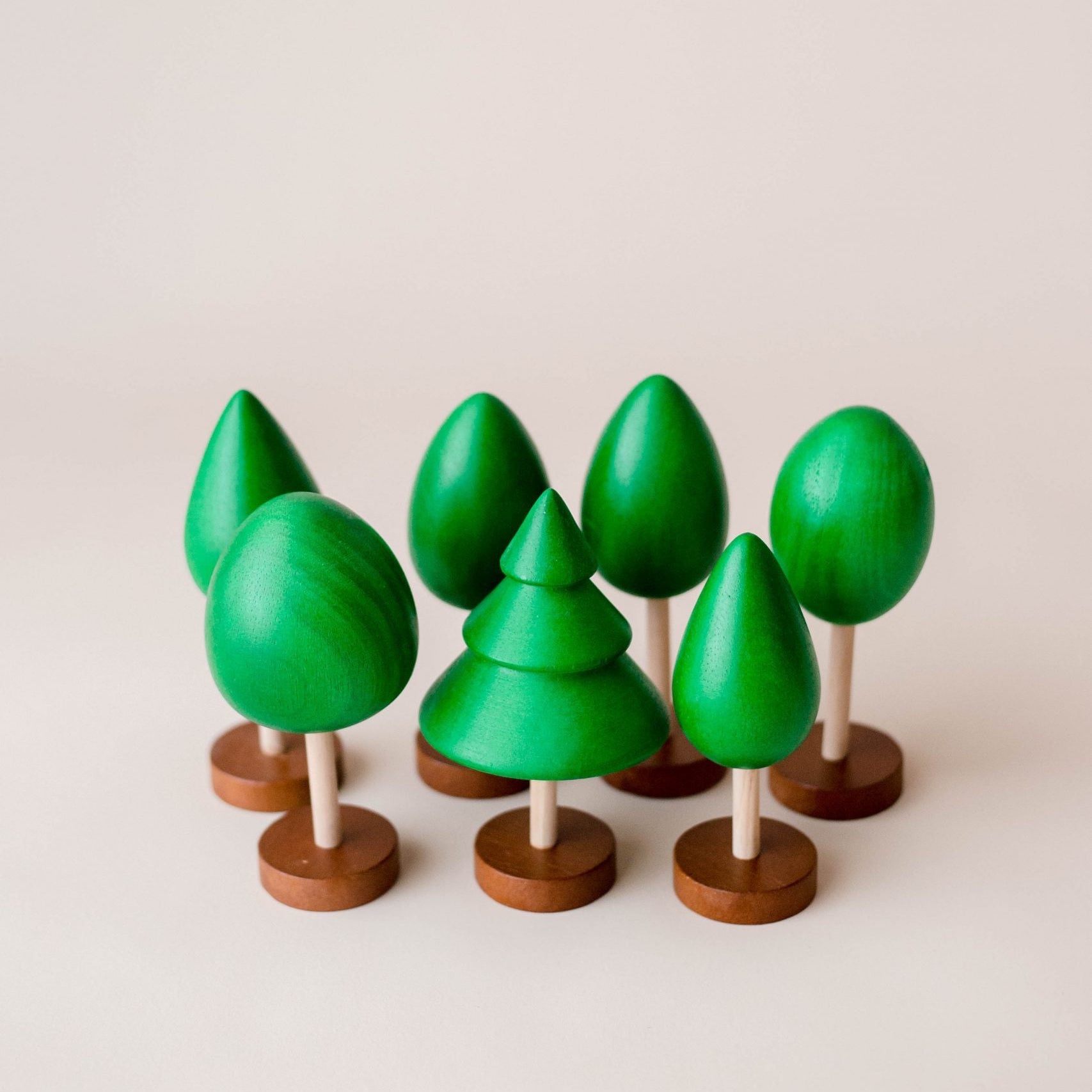 Set of green wooden trees on stands against a light background